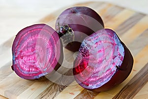 Beets halved on a light wood cutting board