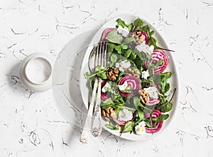 Beets salad with arugula, feta cheese and walnuts. On a light background