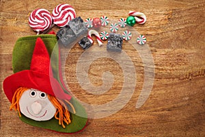 Befana sock with sweet coal and candy on wooden background. Italian Epiphany day tradition.