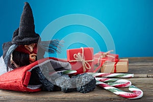 The Befana with sweet coal and candy on wooden background. Italian Epiphany day tradition.