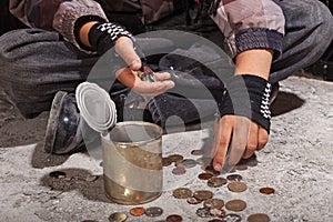 Beggar child counting coins sitting on damaged concrete floor