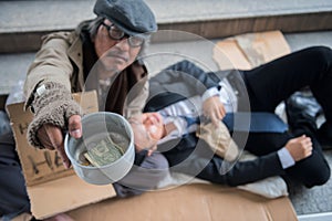 Beggar with drunk Businessman in city