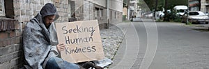 Beggar Showing Seeking Human Kindness Sign On Cardboard