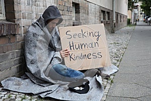 Beggar Showing Seeking Human Kindness Sign On Cardboard photo