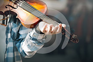 Beggar street musician is playing an old worn out violin