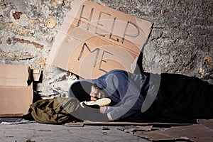 Beggar in tattered clothes sleeping at sidewalk