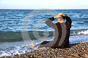 Beggarly barefooted man in suit sits back on coast