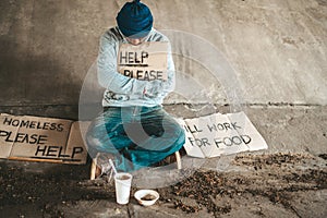 Beggars sitting under the bridge with a sign, help please