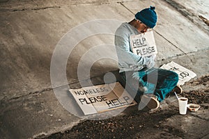 Beggars sitting under the bridge with a sign, help please