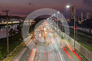 Beggining the night in metropolis, bright lights and vehicles in transit. Sao Paulo city highway beside the river. Skyline