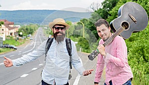Begin adventure. Travelers with backpack and guitar ready to strat new journey. Men at edge of road hitchhiking. Friends