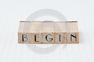 Begin, debut, company establish or start own business concept, wooden stamp with alphabet building the word BEGIN on grid line