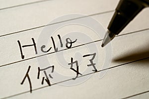 Beginner Chinese language learner writing Hello word in Chinese characters macro shot photo
