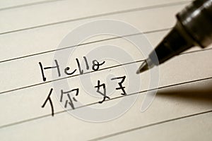 Beginner Chinese language learner writing Hello word Nihao in Chinese characters on a notebook photo