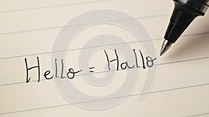 Beginner German or Dutch language learner writing Hello word Hallo for homework on a notebook photo
