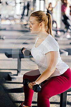 Beginner girl exercising in fitness gym with dumbbells