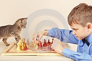 Beginner grandmaster with kitten plays chess.