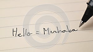 Beginner Turkish language learner writing Hello word Merhaba for homework on a notebook photo