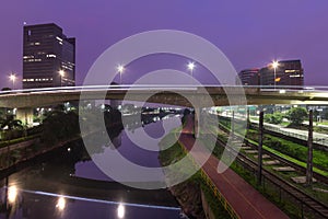 Beginning of the day in metropolis, bright lights and vehicles in transit. Sao Paulo city highway and bridge beside the