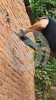 The beginning of the destruction of the wall of the building with a drill to make a hole