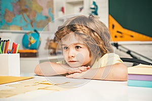 Beginning of lessons. Kids gets ready for school. Happy cute industrious child is sitting at a desk indoors.