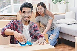 Beginning of married life concept. Asian couple unpacking box after moving to new house