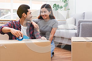 Beginning of married life concept. Asian couple unpacking box after moving to new house