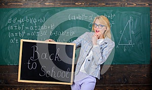 Beginning of new school season. Teacher welcomes school year. Woman teacher holds blackboard inscription back to school