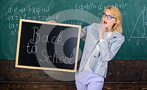 Beginning of new school season. Teacher welcomes school year. Woman teacher holds blackboard inscription back to school