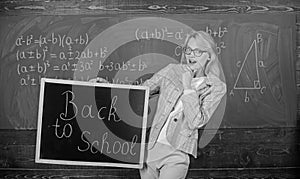 Beginning of new school season. Teacher welcomes school year. Woman teacher holds blackboard inscription back to school