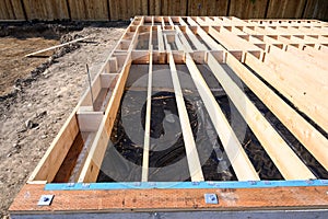 Beginnings of a new home, wood floor joists installed over concrete foundation photo