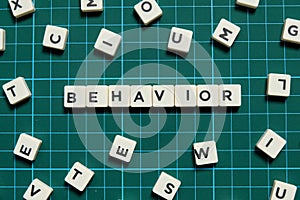 Behavior word made of square letter word on green square mat background.