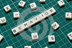 Behavior word made of square letter word on green square mat background.