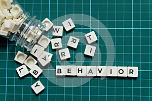 Behavior word made of square letter word on green square mat background.