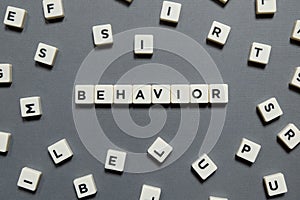 Behavior word made of square letter word on grey background.