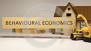 Behavioral economics word written on wooden surface. House and construction concept in background