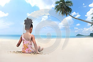 Behind of African girl with black curly hair wearing swimsuit sitting on sand beach outdoor, enjoy playing outside on sunny day at