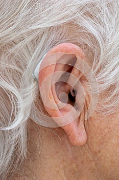 Behind The Ear hearing aid being worn by pensioner.