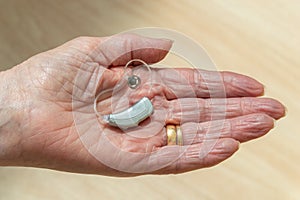 Behind The Ear hearing aid in pensioners hand.