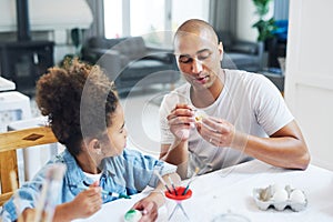 Behind every great daughter is a truly amazing dad. a man painting eggs with his daughter at home.