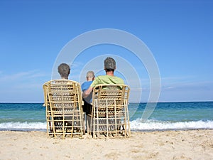 Behind family on easychairs on beach