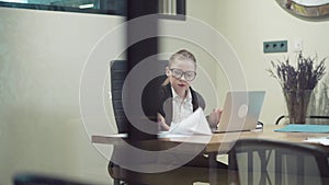 Behind the glass, a business woman is in a hurry and is late to submit a report.