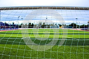 Behind goalie`s goal net. football and soccer field grass stadium