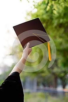 Behind photo of university graduate wears gown and black cap, ye