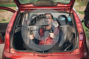 Behind scene improvisation. Cameraman from trunk of car shooting photo