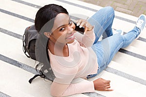 Behind of smiling young african american woman smiling with mobile phone
