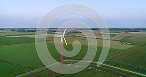 Behind a Wind Turbine is a Tractor Working on a Field - Friesland, The Netherlands, 4K Drone Footage