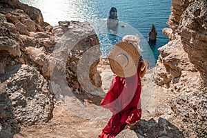 From behind, a woman is seen in a red flying dress fluttering in the wind. In a straw hat, walking down the stairs