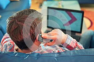 Behind of young guy using laptop and phone