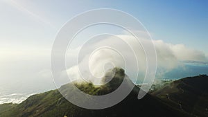 Behold the beauty of the skies. 4k drone footage of clouds around a mountaintop along the coast.